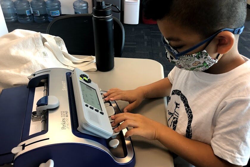 a young boy wearing a face mask and using a machine.