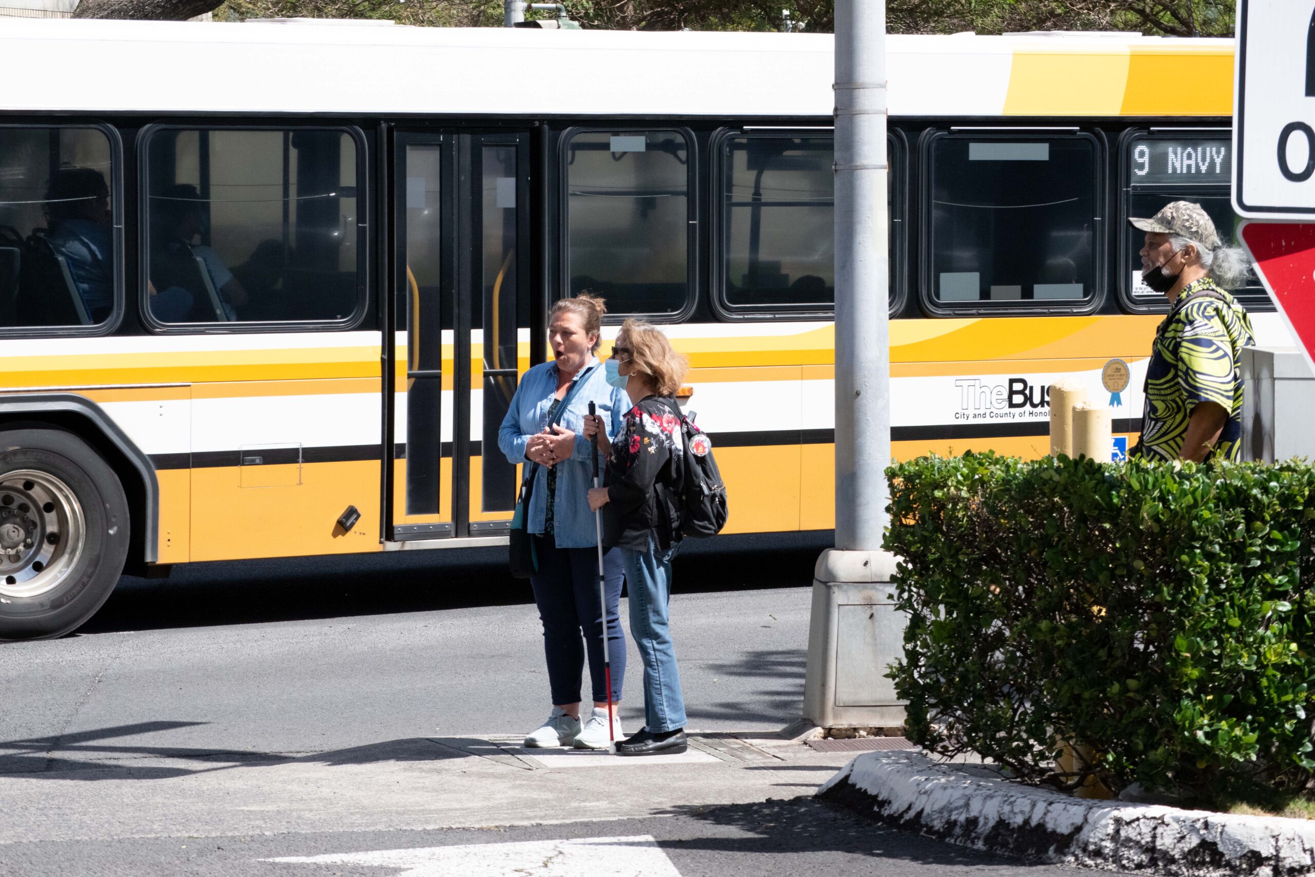 a couple of women standing next to a yellow and white bus.